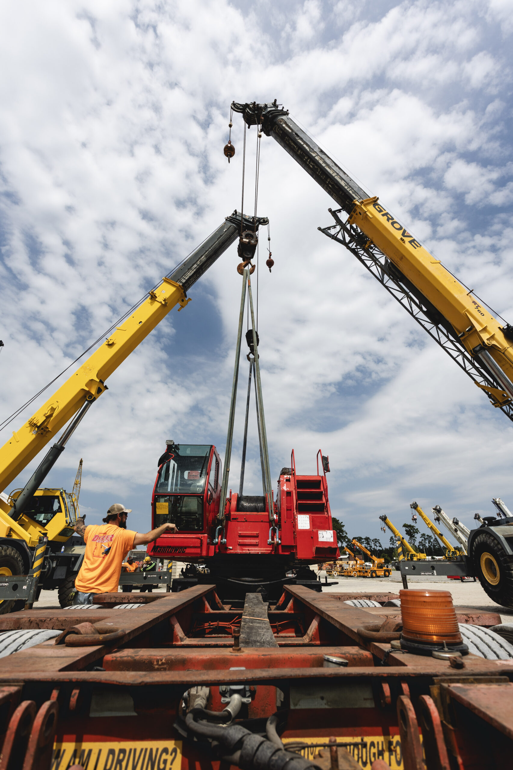 Heavy Hauling and Lifting equipment pictured in action with Dozier Crane employees lifting a crane onto a truck bed.