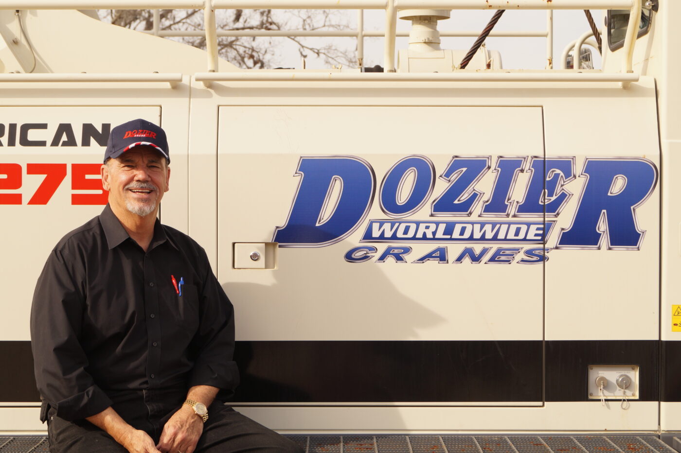 Dozier Cook sitting on a crane wearing a hat and black shirt