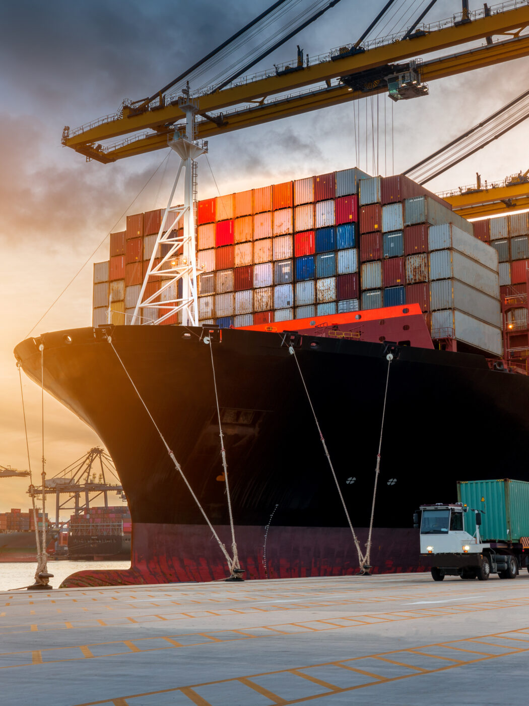 crane loading cargo container from truck to container ship in the international terminal logistic sea port concept freight shipping by ship
