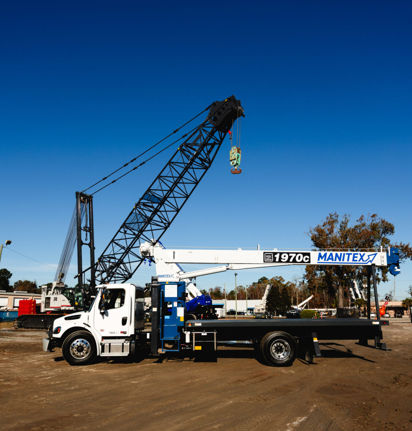 White boom truck crane parked in an equipment yard.